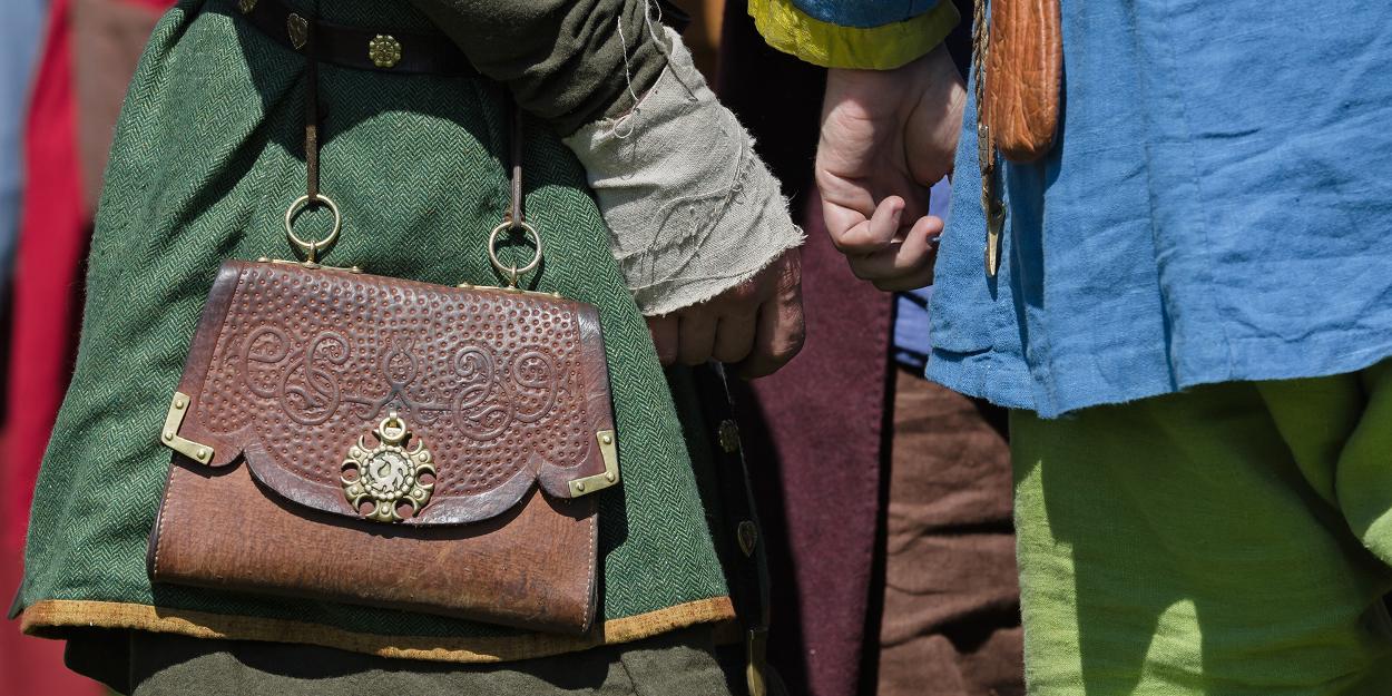 People at faire in medieval clothing with handmade leather handbag