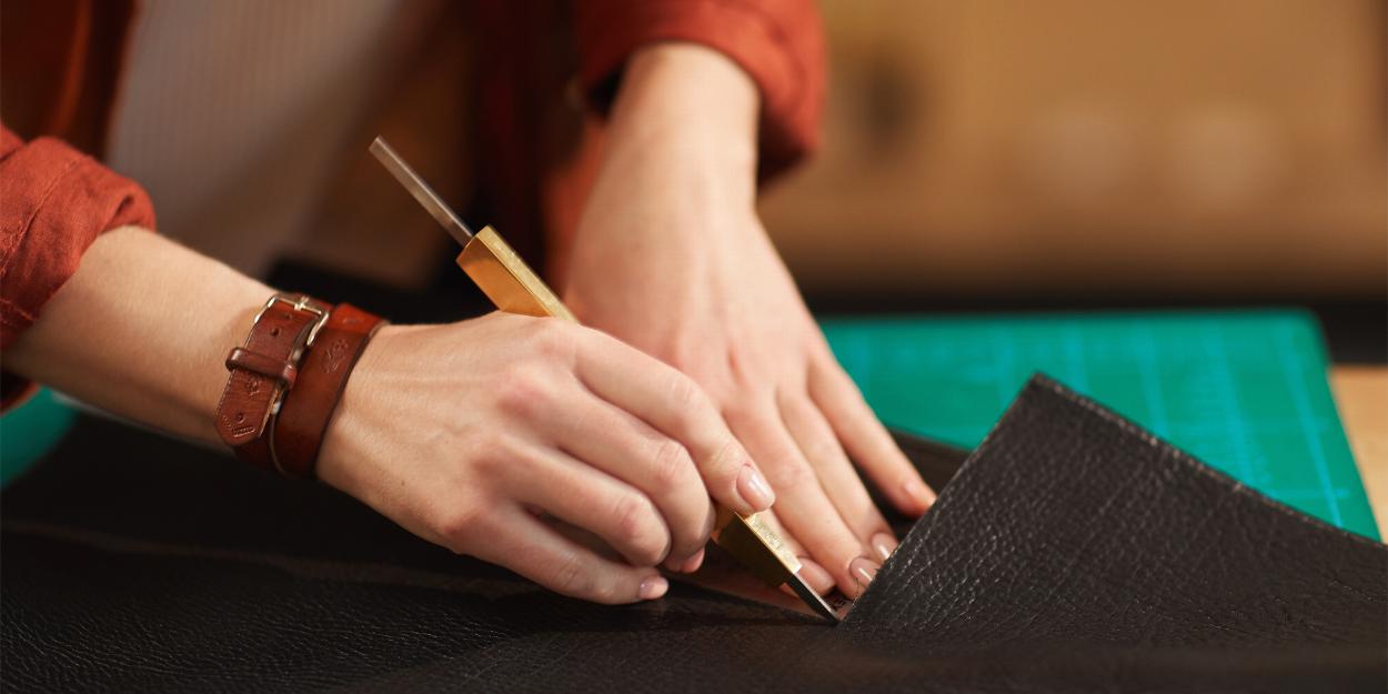 Hands tooling a piece of leather